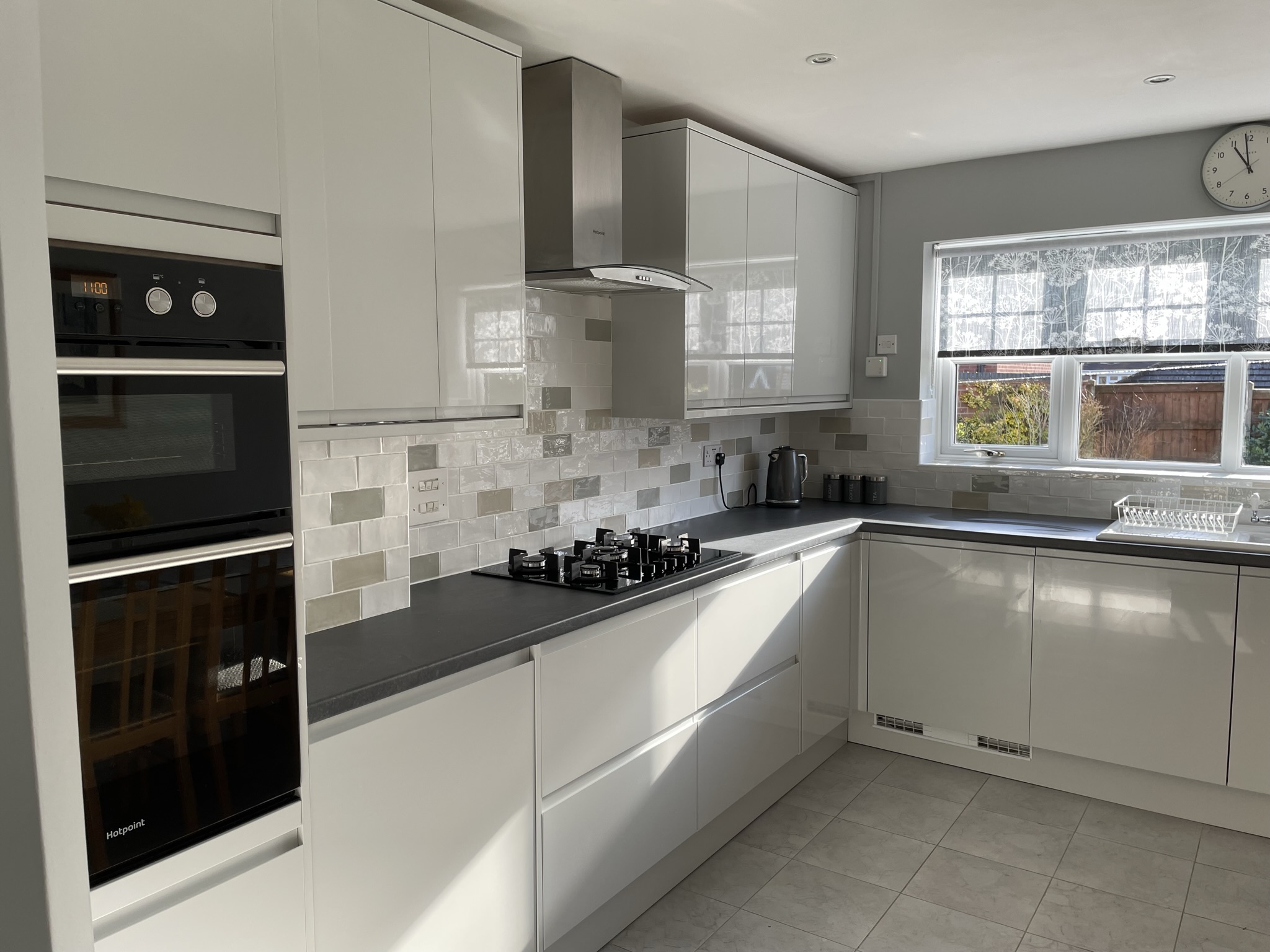 High gloss grey units with complementing dark grey worktops and wall tiling